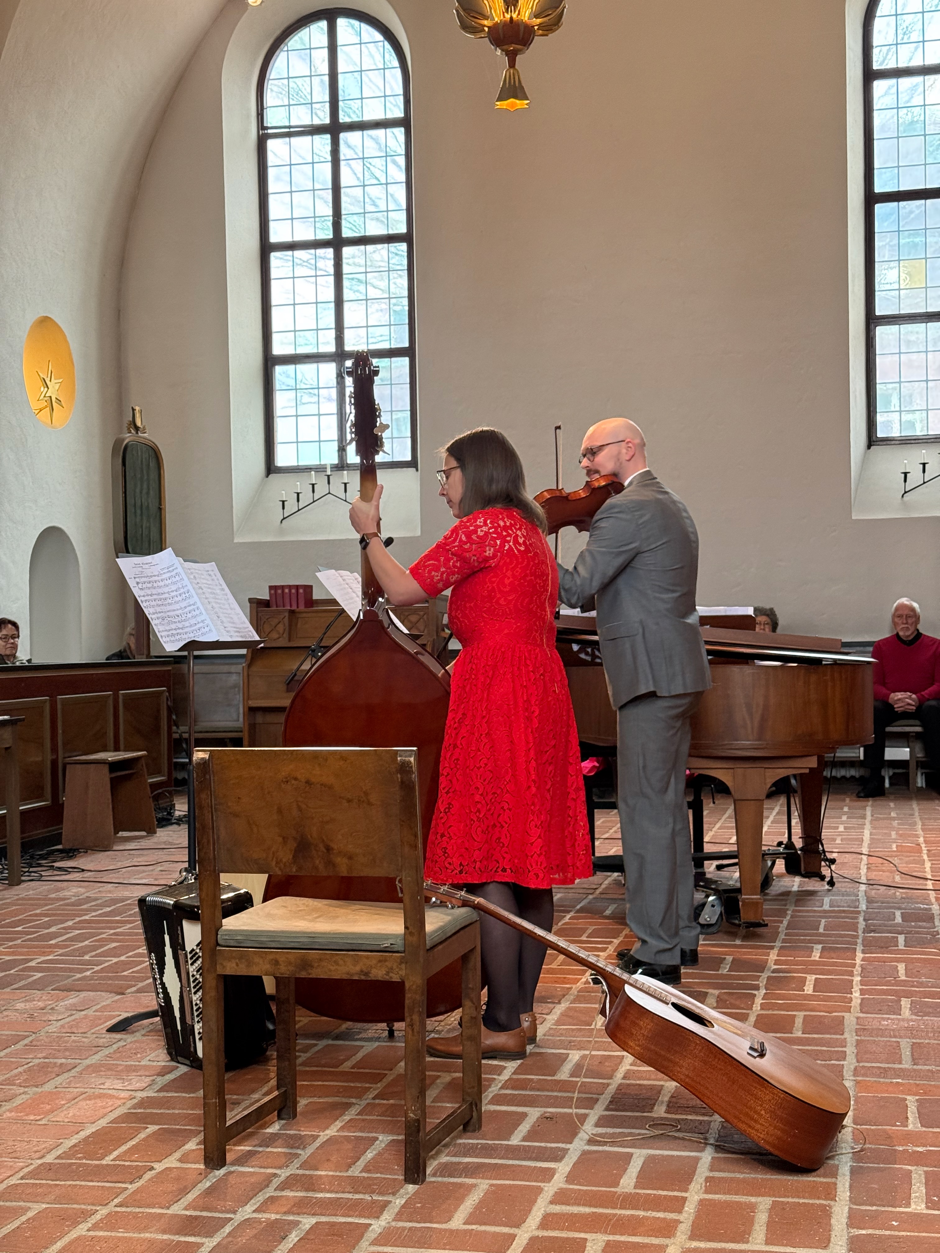 Julia spelar kontrabas tillsammans med en violinist under en konsert i en kyrka.