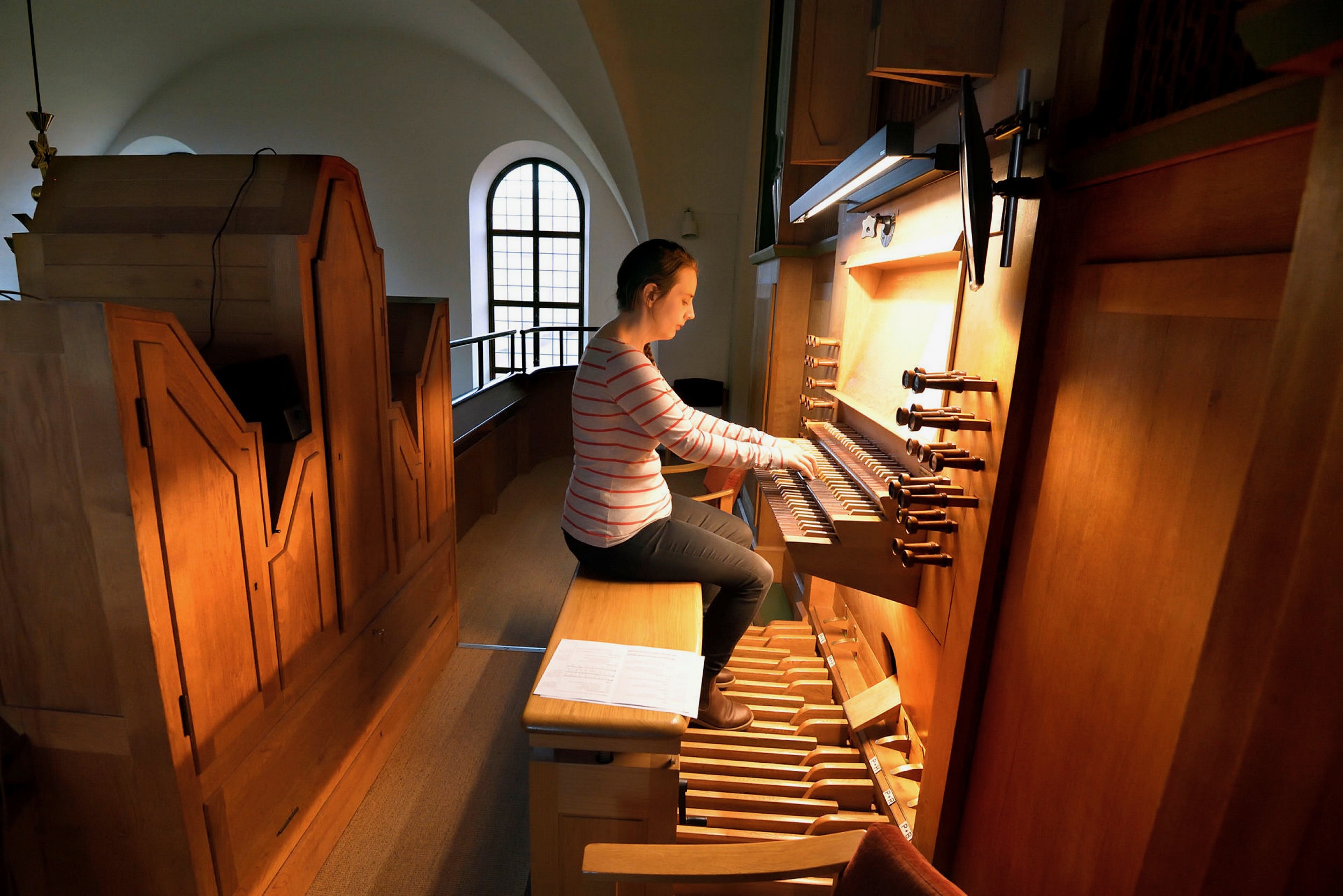 Julia spelar kyrkorgel på en läktare i en kyrka.